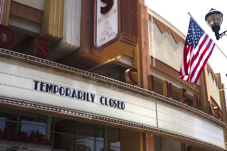 The exterior of a movie theater has the words 'temporarily closed' posted.