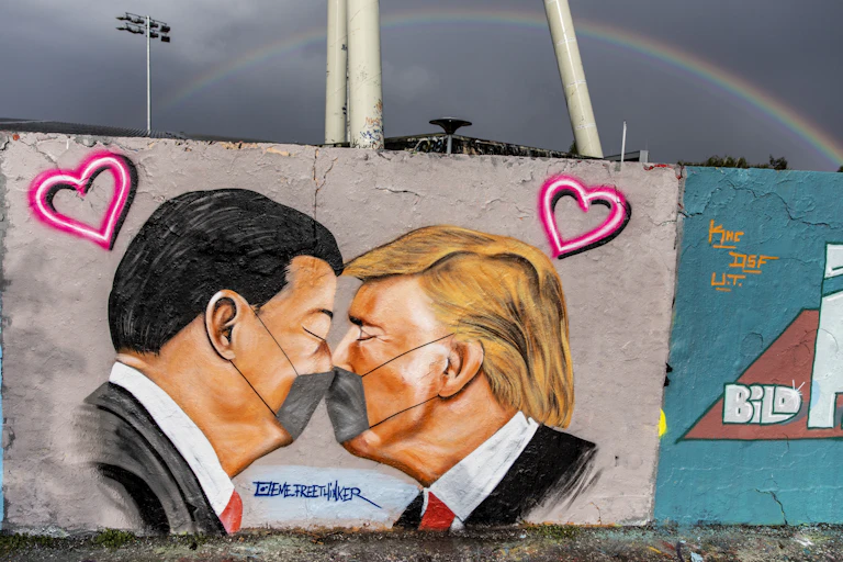 Grafitti artwork showing Xi Jinping and Donald Trump kissing with masks on.