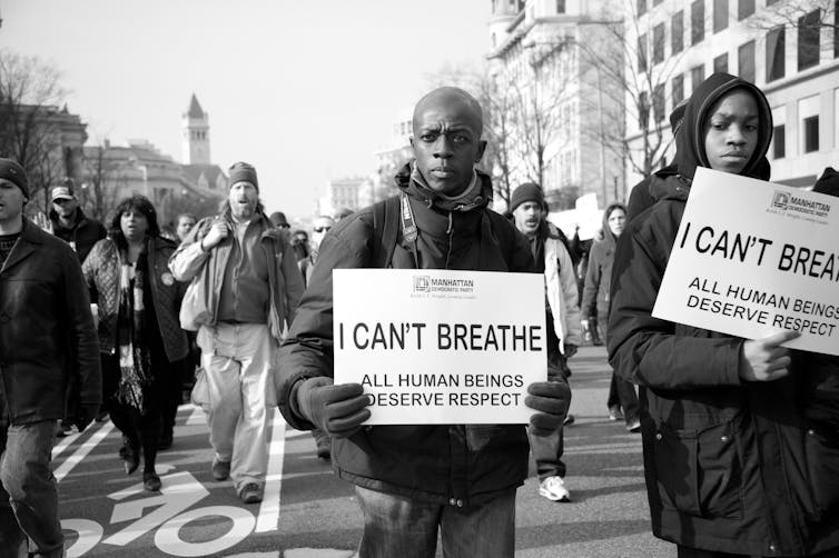 Two Black men carry posters with the words, 'I Can't Breathe'