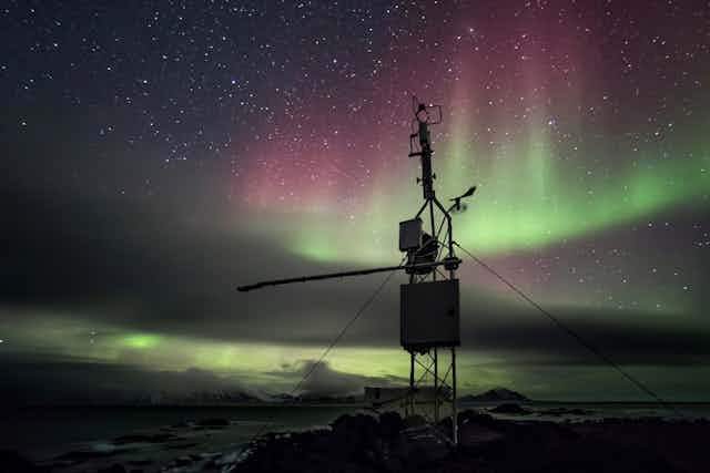 Estación meteorológica en el Ártico, con una aurora boreal de fondo.