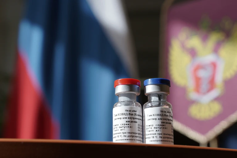 two vials of vaccine in front of Russian flag