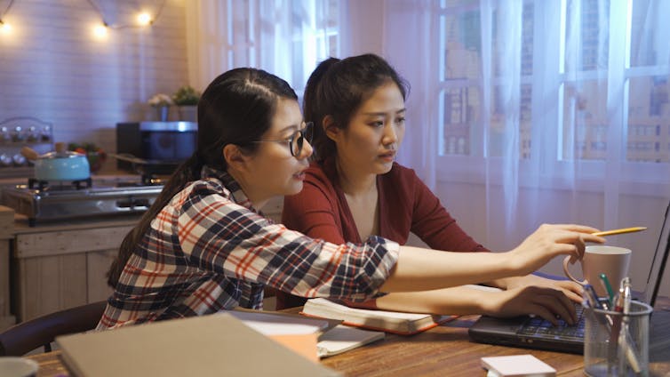 Two students sitting at a table together and working out a problem