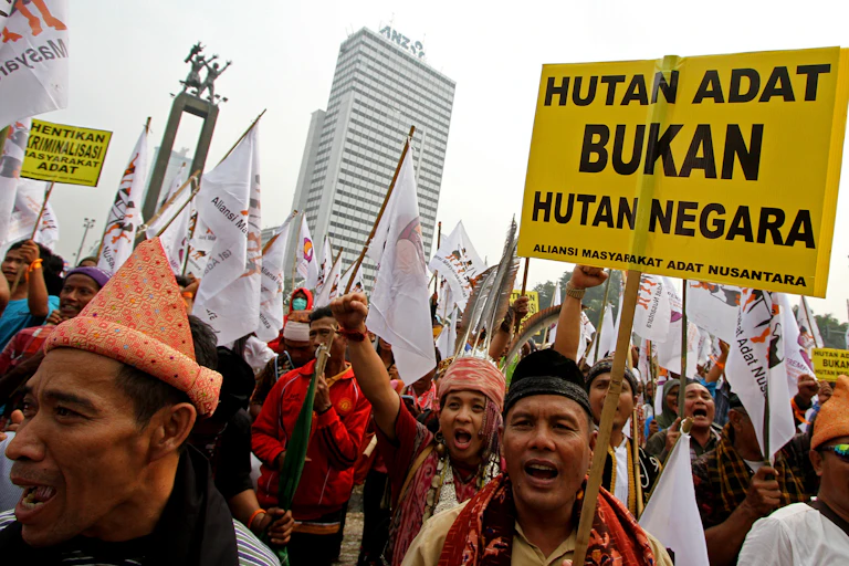 Dozens of men wearing traditional outfits holding protest signs.