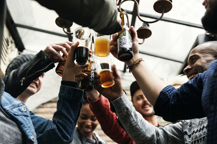 A group of colleagues chinking glasses in a bar.