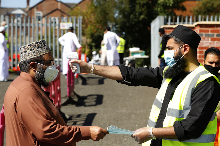 A man has his temperature taken before entering a Mosque in Rochdale, Greater Manchester.
