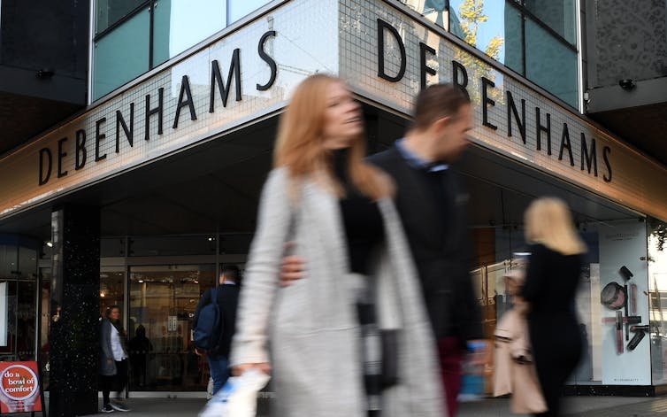Shoppers walking past Debenhams