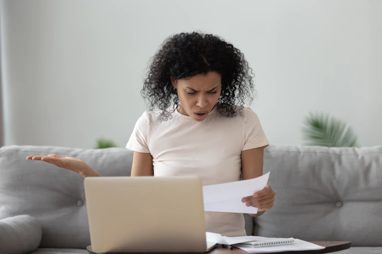 Young woman looks shocked at paper