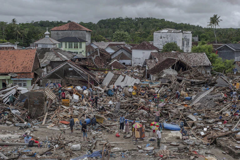 People mill around building debris
