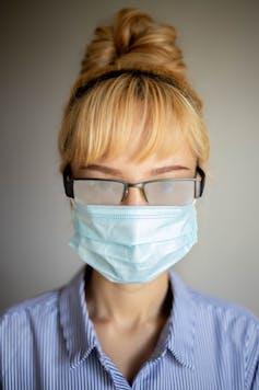 A woman wearing a face mask and eyeglasses with fogged-up lenses