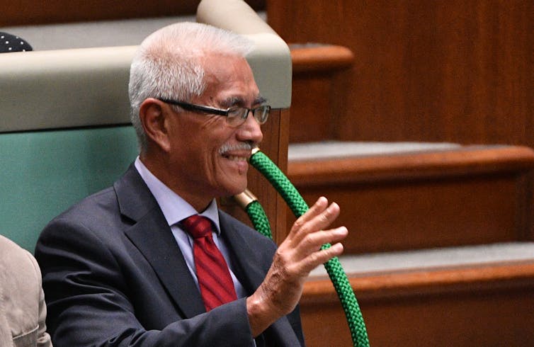 Former Kiribati president Anote Tong raises his hand while sitting in Australian parliament during question time.