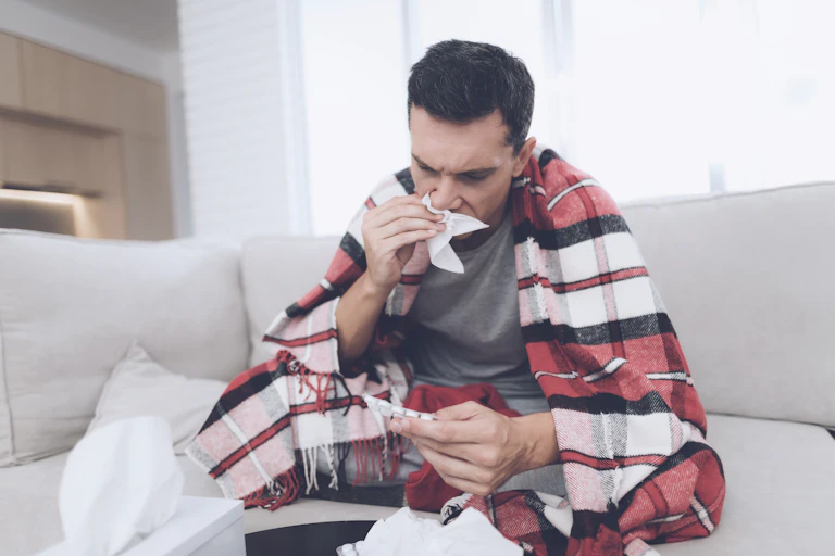 A man who is feeling sick and using tissues