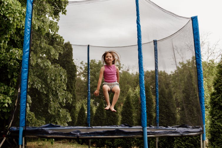 A young girl bouncing on a trampoline.