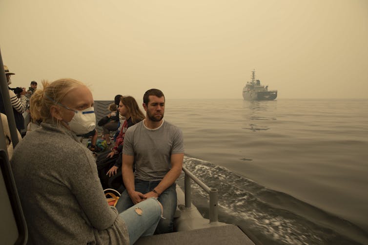People on a boat wearing masks, surrounded by a haze.
