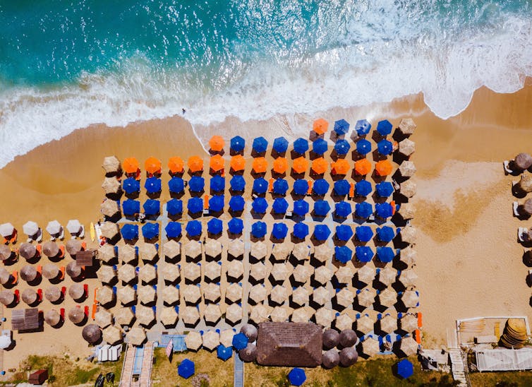 Aerial view of beach with sun umbrellas.