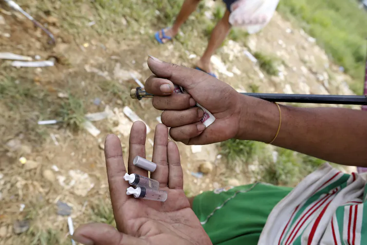 A man's hands holding heroin and money in Myanmar.