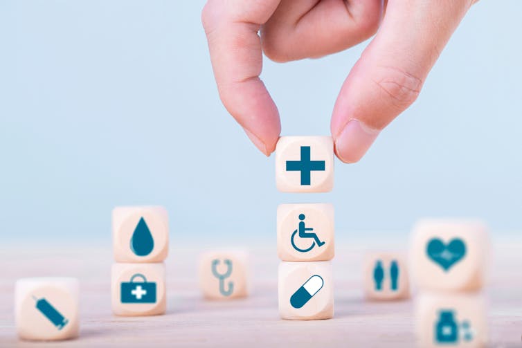 Hand building tower of dice with medical symbols on them