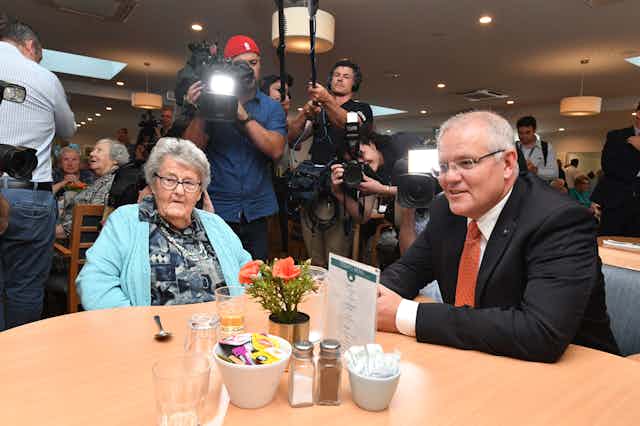 Scott Morrison sitting at a table with an elderly lady, at an aged care visit