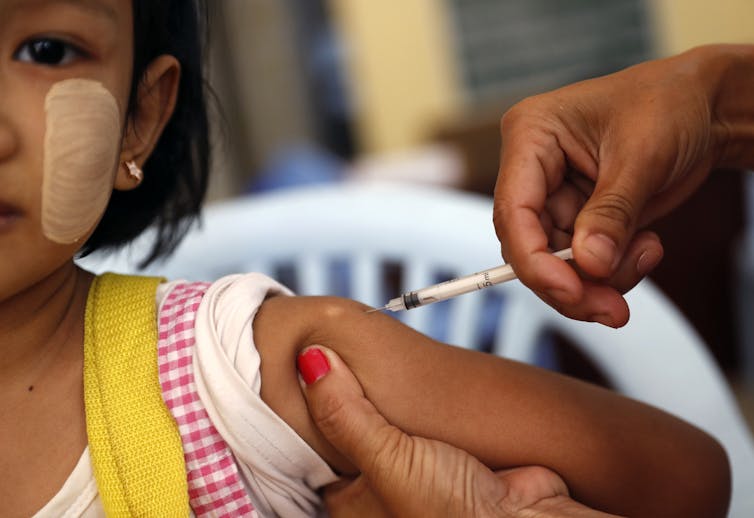 Girl receiving injection in arm.