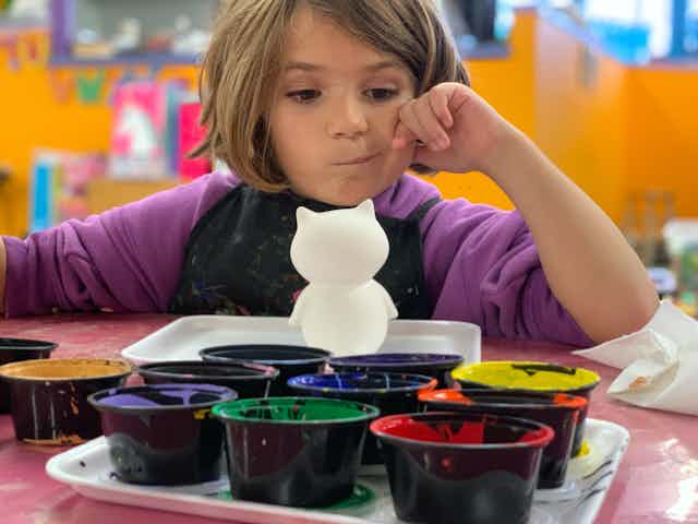 A young girl contemplates paint colours at a daycare centre.