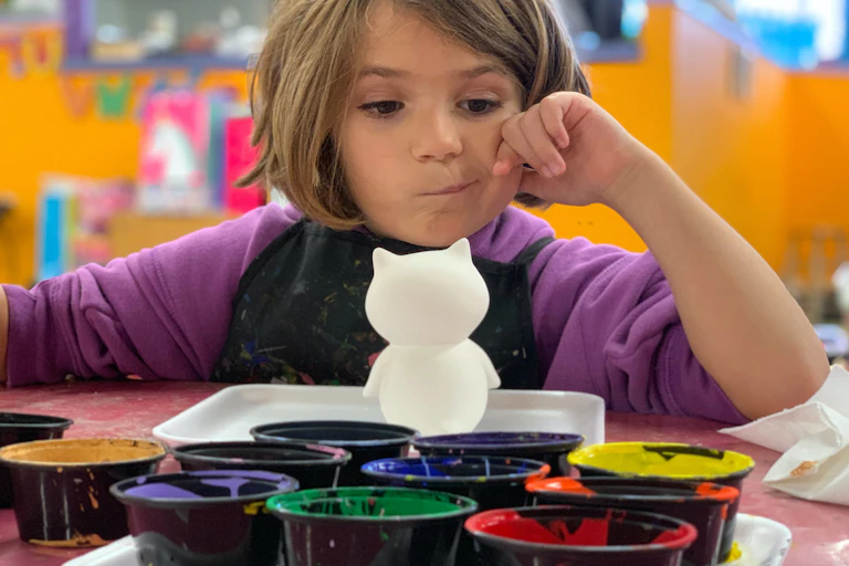 A young girl contemplates paint colours at a daycare centre.