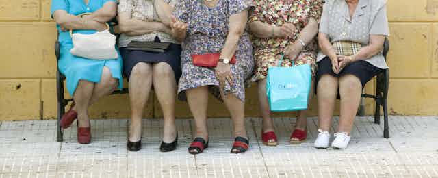 Cuatro señoras mayores sentadas en un banco.