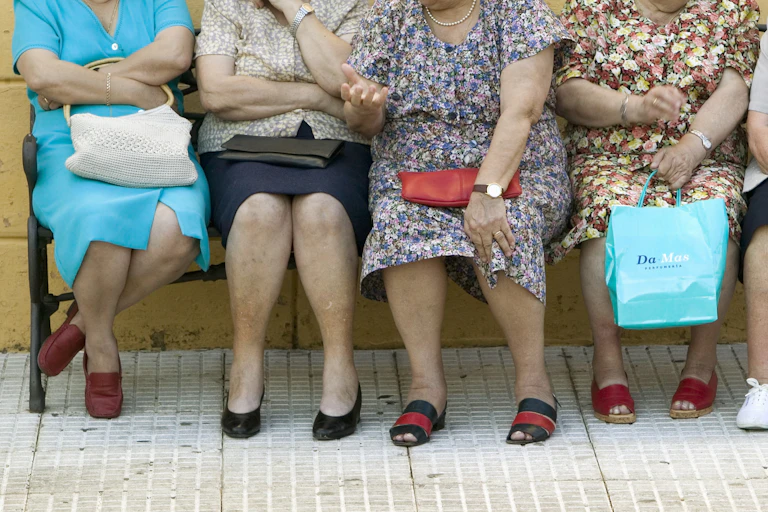 Cuatro señoras mayores sentadas en un banco.