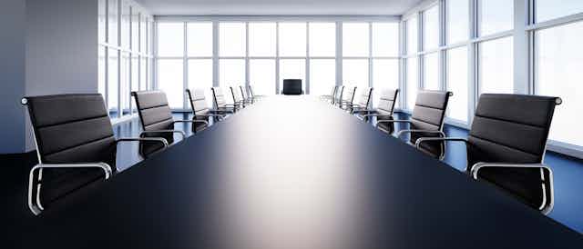 Sala de reuniones con gran mesas rodeada de sillas.