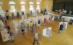 A polling place in a public building with booths and voters.