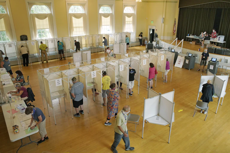 A polling place in a public building with booths and voters.