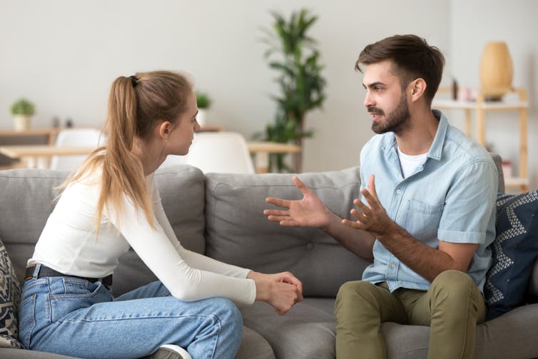 Young couple on sofa talking to each other