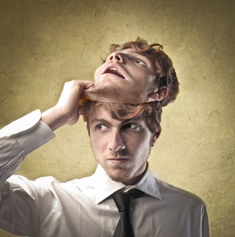 Man pulling a mask of his face off his head.