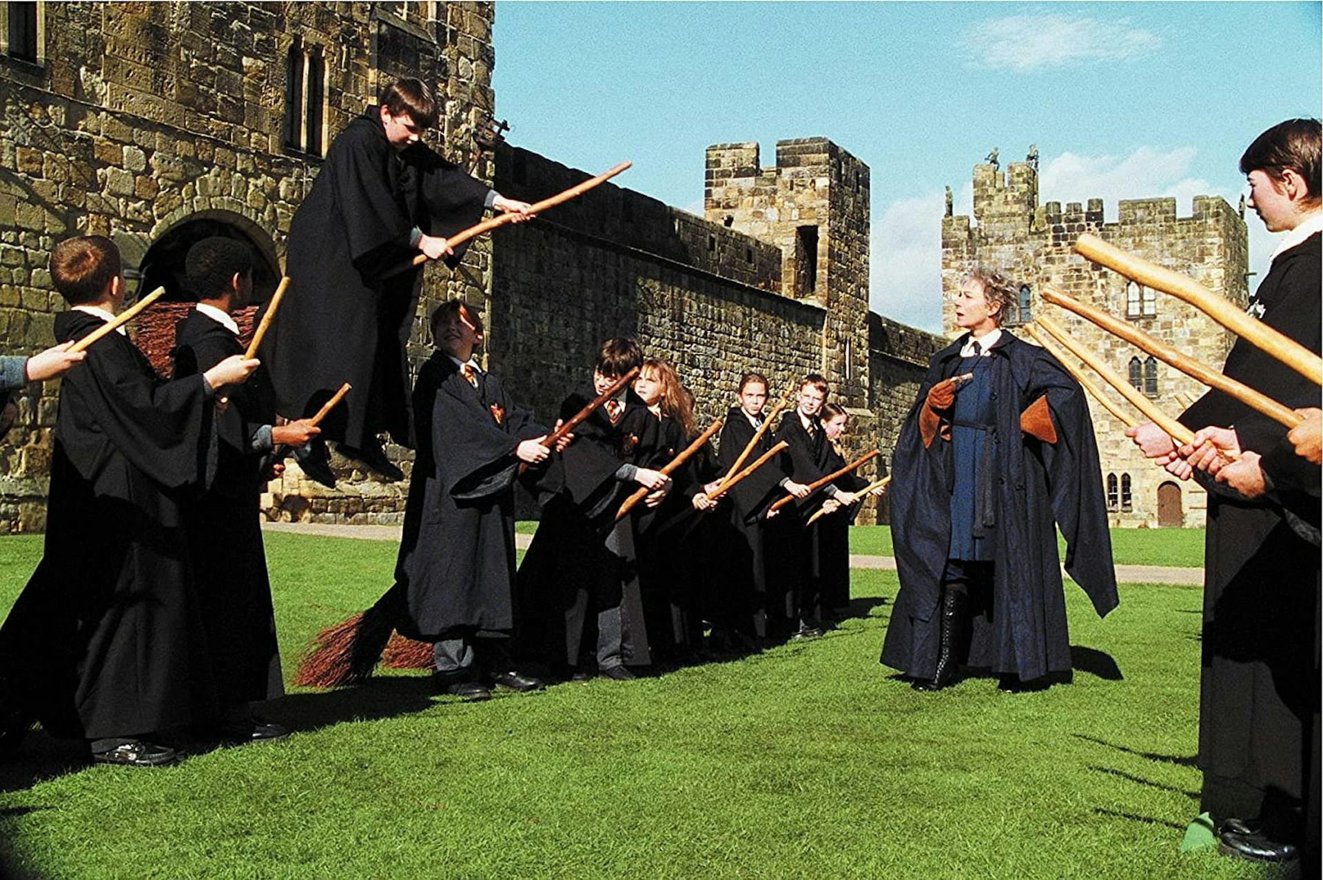 mustiin kaapuihin pukeutuneet nuoret yrittävät ratsastaa luudilla Harry Potter-elokuvassa.