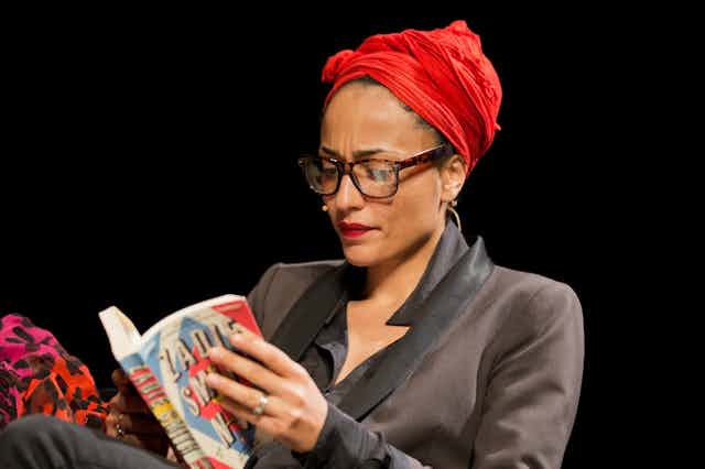 Zadie Smith in a red turban adn black suit reads from her book NW.