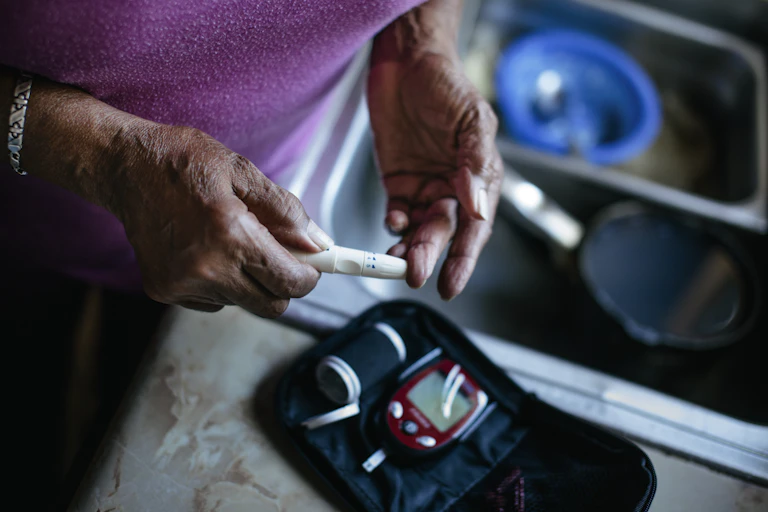 An elderly woman's hands shown as she self-tests using a medical testing kit
