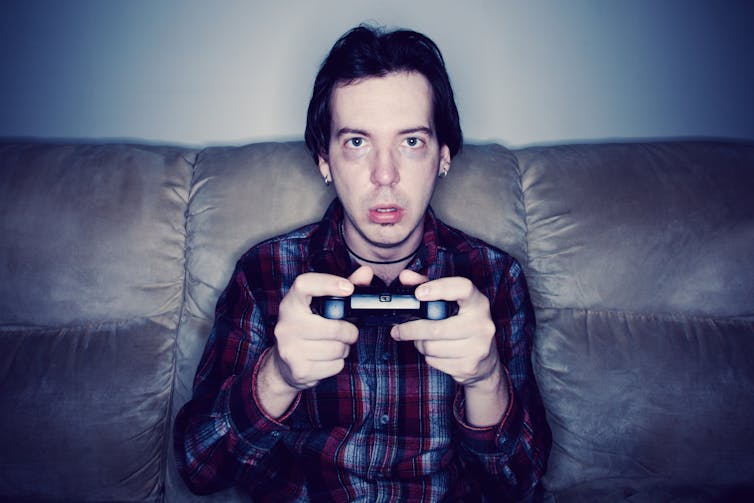 Tired-looking man on a couch holding a game controller