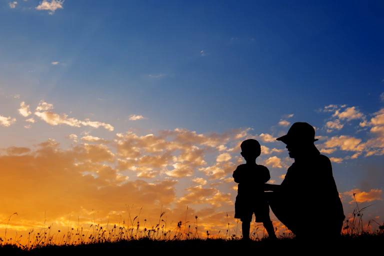 Silhouette of mother playing with small son.