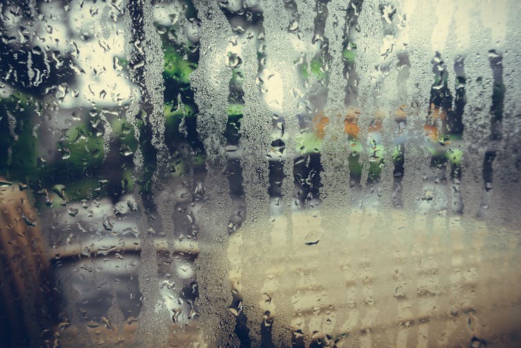 Condensation on a window which looks outside to a table and chair.