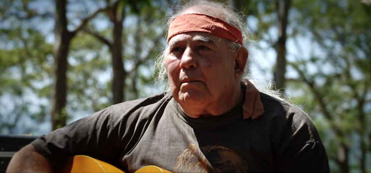 Indigenous man sings with guitar