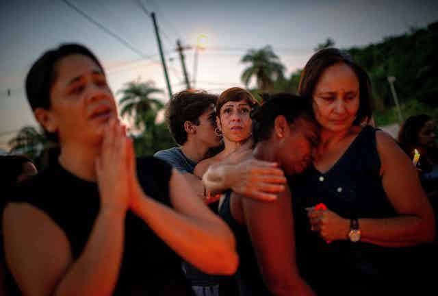 Women mourn after a dam collapse in Brazil.