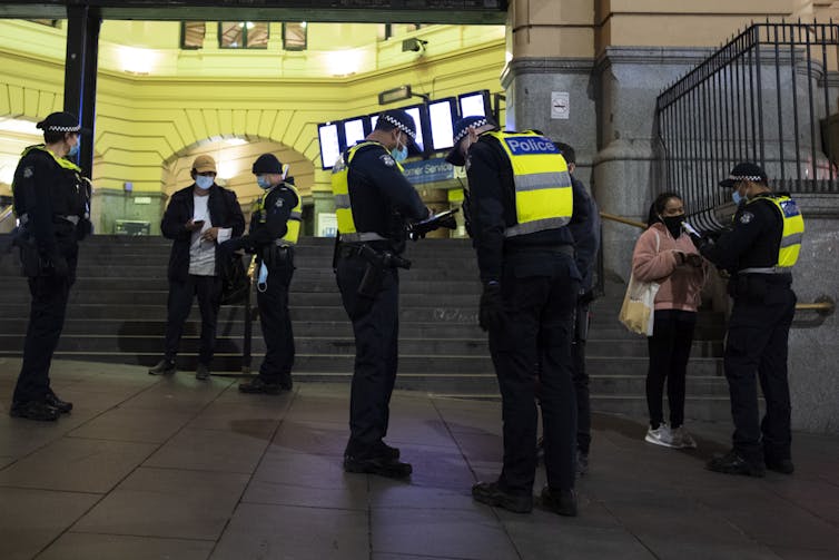 Victoria police check travel permits in front of Melbourne's Flinders Street Station.