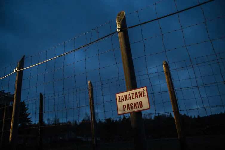 Fence at Vojna labour camp in Czech Republic with sign in Czech.