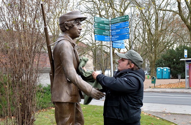 A man installing a statue of a young resistance fighter at Statue Park in Budapest, Hungary.