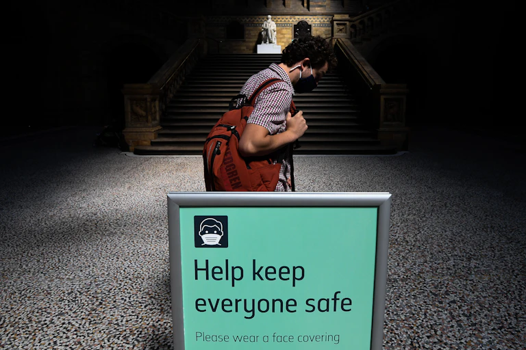 A man in a mask walks through the Natural History Museum in London.