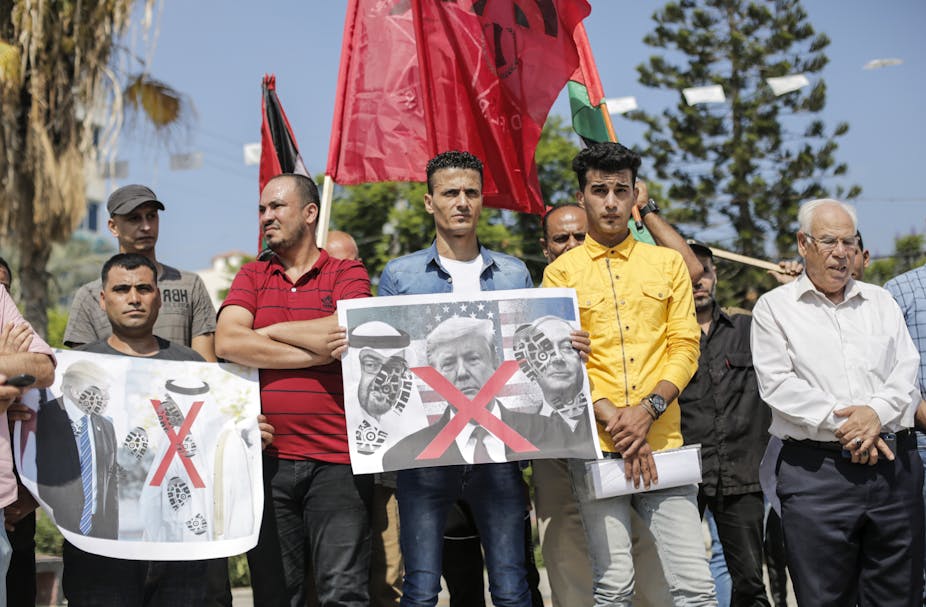 Palestinians hold signs with red X across the faces of US, Israeli and Emirati leaders