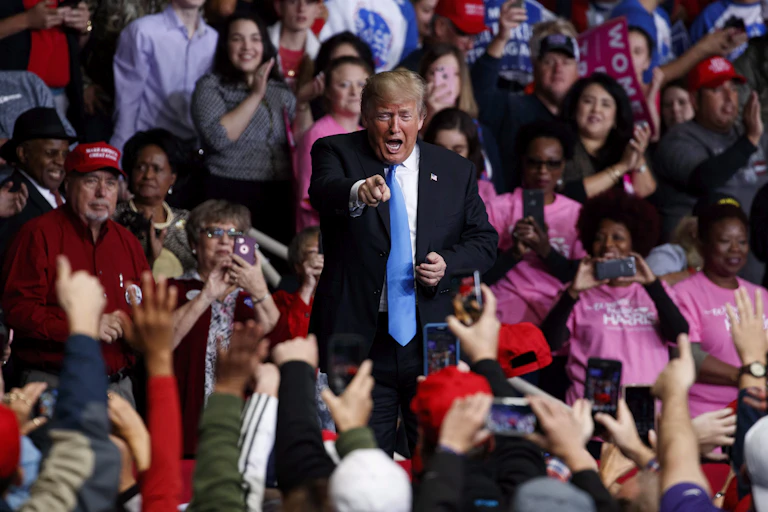 U.S. President Donald Trump appearing in a crowd of supporters at a campaign rally in 2018 in Charlotte, N.C.
