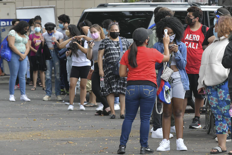 A line of students and parents waits to have their temperature taken before entering Hollywood High School.