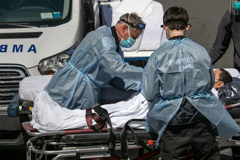 Medics stand over a gurney and help a patient.