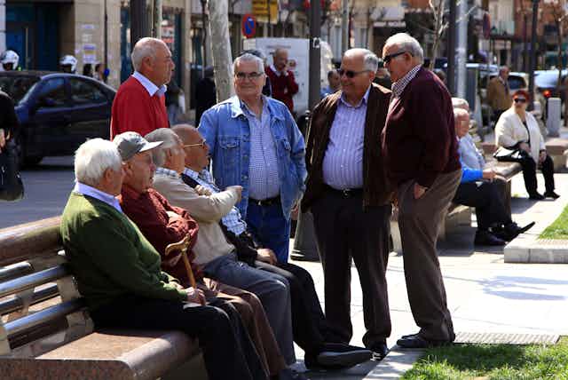 Ocho señores mayores en un banco de una plaza de Madrid.