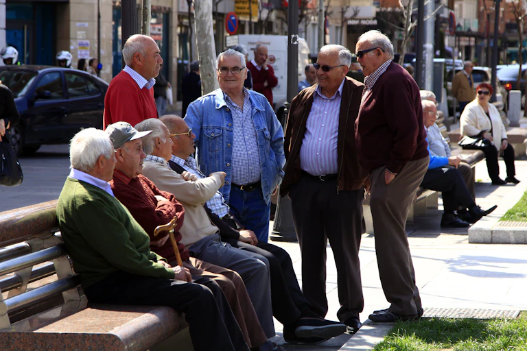 Ocho señores mayores en un banco de una plaza de Madrid.