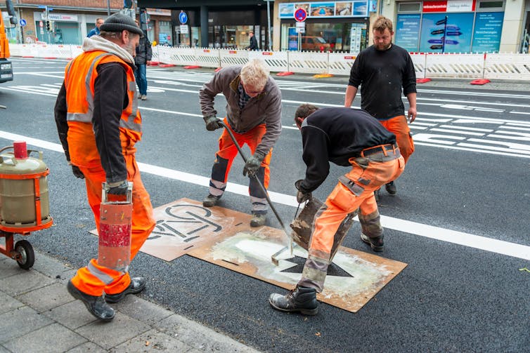 Road workers apply a bicycle symbol on the road